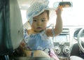 Close up portrait of sweet and adorable Asian Chinese baby girl in beautiful hat hold by her mum inside a car in family lifestyle Royalty Free Stock Photo