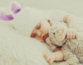 Portrait of sweet baby sleeping with teddy bear toy on a white bed at home Royalty Free Stock Photo