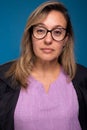 Close-up portrait of sweet confident female doctor dressed in black coat and lilac uniform, wearing eyeglasses, looking at camera Royalty Free Stock Photo