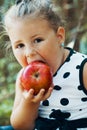 Portrait of a sweet little happy girl while eating an apple Royalty Free Stock Photo