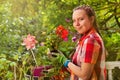 Smiling girl holding geranium plant on terrace