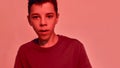 Close up portrait of teenaged disabled boy with cerebral palsy looking at camera, posing isolated over red light Royalty Free Stock Photo