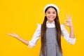 Close up portrait of teenager child girl showing at copy space, pointing to ads advertising, isolated over yellow