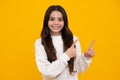 Close up portrait of teenager child girl showing at copy space, pointing to ads advertising, over yellow