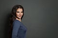 Close-up portrait of tender brunette woman with curly hair smiling joyfully on gray background Royalty Free Stock Photo