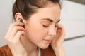 Close up portrait of tender, smiling and cute woman, puts on black wireless earphones in her ears, listens to music Royalty Free Stock Photo