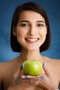 Close up portrait of tender young girl holding apple over blue background Royalty Free Stock Photo