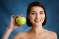 Close up portrait of tender young girl holding apple over blue background Royalty Free Stock Photo