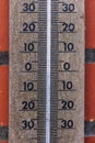 A close up portrait of a thermometer gauge showing a temperature measurement of zero degrees celcius. The intstrument is hanging
