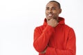 Close-up portrait of thoughtful young daydreaming african-american man, touching chin and looking away with pleased