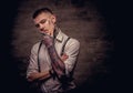 Close-up portrait of a young old-fashioned tattooed guy wearing white shirt and suspenders. on dark background. Royalty Free Stock Photo