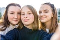 Close-up portrait, three girls schoolgirls teenagers, summer outdoors. Photography on phone, selfie photo, online app