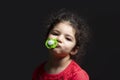 Close-up portrait of a three years old girl with pacifier in front of dark background