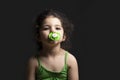 Close-up portrait of a three years old girl with pacifier and green stirrup in front of dark background Royalty Free Stock Photo