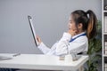 Close up portrait of tired female doctor sitting at the desktop and working on laptop in the office of modern clinic Royalty Free Stock Photo