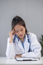 Close up portrait of tired female doctor sitting at the desktop and working on laptop in the office of modern clinic Royalty Free Stock Photo