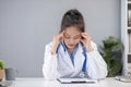 Close up portrait of tired female doctor sitting at the desktop and working on laptop in the office of modern clinic Royalty Free Stock Photo