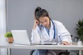 Close up portrait of tired female doctor sitting at the desktop and working on laptop in the office of modern clinic Royalty Free Stock Photo