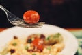 Close-up portrait of tomato on the fork with blurry background of salad Royalty Free Stock Photo