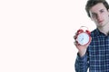 Close-up portrait of a troubled young man holding alarm clock isolated over white background. Royalty Free Stock Photo