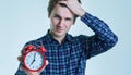 Close-up portrait of a troubled young man holding alarm clock isolated over white background. Royalty Free Stock Photo