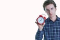 Close-up portrait of a troubled young man holding alarm clock isolated over white background. Royalty Free Stock Photo