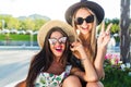 Close-up portrait of two attractive blond and brunette girls with long hair posing to the camera in park. They wear Royalty Free Stock Photo