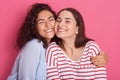 Close up portrait of two attractive caucasian smiling women iposing solated on over pink studio background, brunettef emales Royalty Free Stock Photo