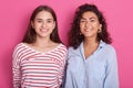 Close up portrait of two attractive dark haired caucasian smiling women isolated onver pink studio background, beautiful ladies Royalty Free Stock Photo