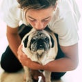 Close up and portrait of two best friends at home together - teenager kissing the head of a pug - pet and domestic dog concept Royalty Free Stock Photo