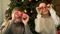Close up portrait of two cheerful, positive couple holding round glossy toys, covering eyes, fooling around on decorated