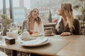 Close-up portrait of two female friends in strict suits laughing drinking coffee and wine on the terrace outside at Royalty Free Stock Photo