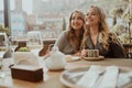 Close-up portrait of two female friends in strict suits laughing drinking coffee and wine on the terrace outside at Royalty Free Stock Photo