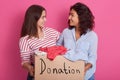 Close up portrait of two girls volunteering, women holding box with clothes for poor people, attractive female making donation,