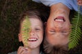 Close up portrait of two happy smiling brothers lying on green grass. Cheerful kids laughing together Royalty Free Stock Photo