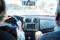 Close up and portrait of two mature people in a car looking at the road or street - pensioner senior driving a car and man sitting