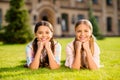 Close-up portrait of two nice attractive charming lovely cute cheerful cheery pre-teen girls lying in green grass fresh Royalty Free Stock Photo