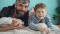 Close-up portrait of two people adult father and cute little son lying on bed at home and smiling. Paternal love