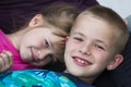Close-up portrait of two small cute blond happily smiling children, brother and sister, boy and girl laying in bed under colorful Royalty Free Stock Photo