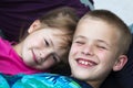 Close-up portrait of two small cute blond happily smiling children, brother and sister, boy and girl laying in bed under colorful Royalty Free Stock Photo