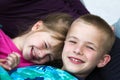 Close-up portrait of two small cute blond happily smiling children, brother and sister, boy and girl laying in bed under colorful Royalty Free Stock Photo