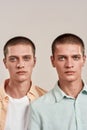 Close up portrait of two young caucasian twin brothers looking at camera while posing together in studio, standing Royalty Free Stock Photo