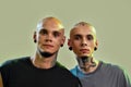 Close up portrait of two young men, twin brothers with tattoos and piercings looking at camera, posing together