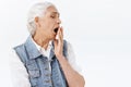 Close-up portrait, unamused and bored, indifferent or tired old woman, senior lady yawning and turn face away with