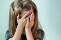 Close-up portrait of unhappy little girl with long hair covering her face with hands crying