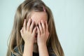 Close-up portrait of unhappy little girl with long hair covering her face with hands crying Royalty Free Stock Photo