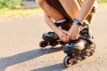 Close up portrait of unknown child squats on road and fixing laces on roller blades before skating, faceless kid having fun Royalty Free Stock Photo