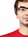 Close-up portrait of unshaved emotionless man in glasses and red t-shirt half-face over white background Royalty Free Stock Photo