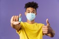 Close-up portrait of upbeat young hispanic man in medical mask holding ampoule with vaccine, coronavirus drug