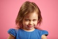 Close up portrait of upset little girl three years on pink isolated background, expresses frustration or resentment